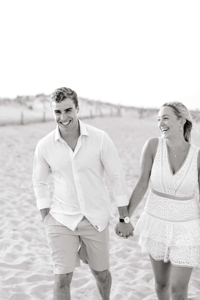 Elegant beach couple photography with candid smiles and holding hands.
