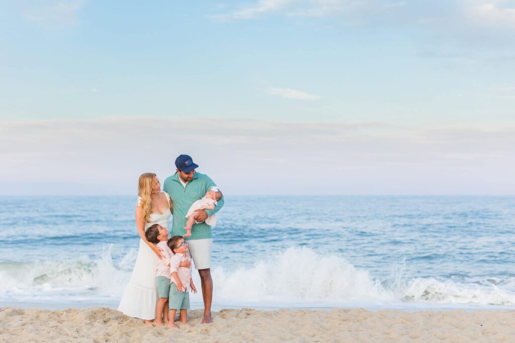 A joyful family of five enjoying a sunny day on the beach, capturing precious moments by the ocean.