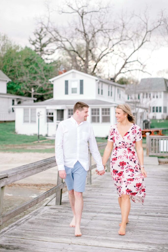 Beautiful couple holding hands on a rustic pier, celebrating love outdoors.