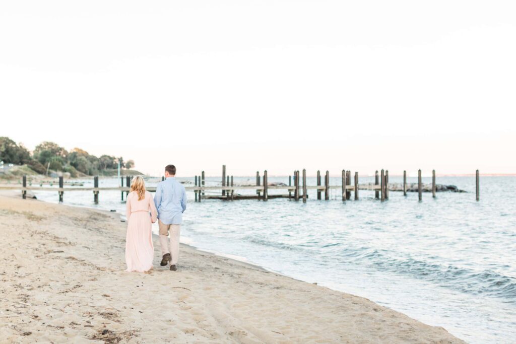 Sunset beach engagement photo of a couple walking hand in hand.