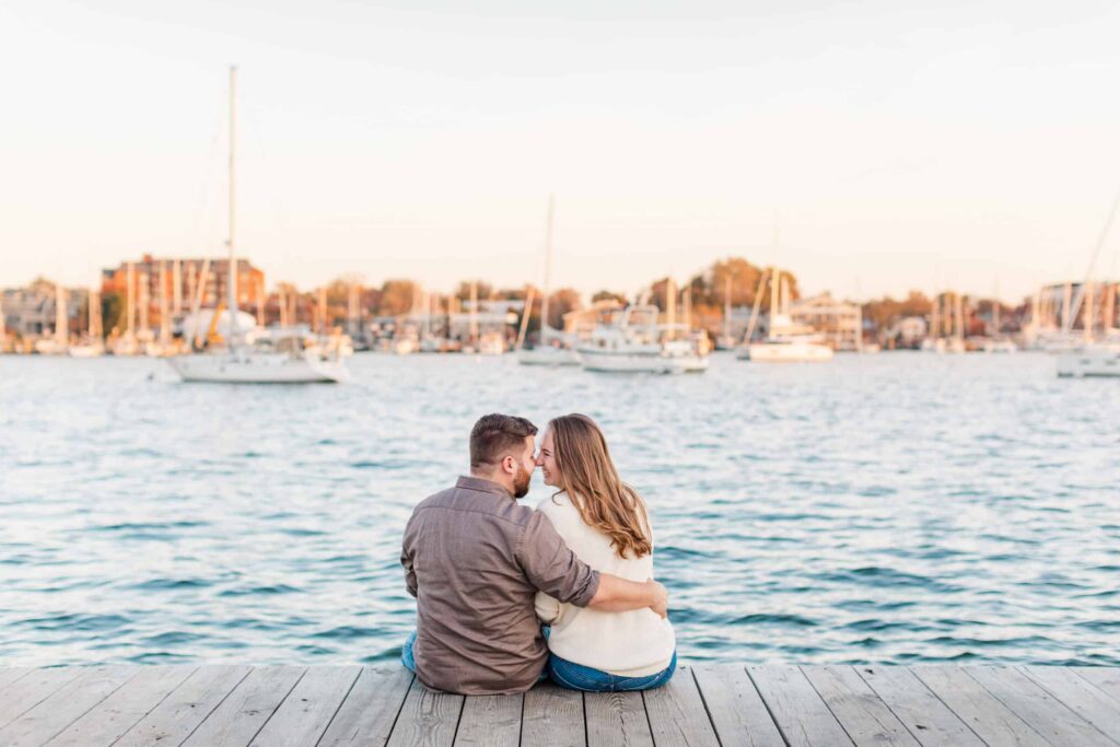 Romantic waterfront couple sitting on dock with boats.