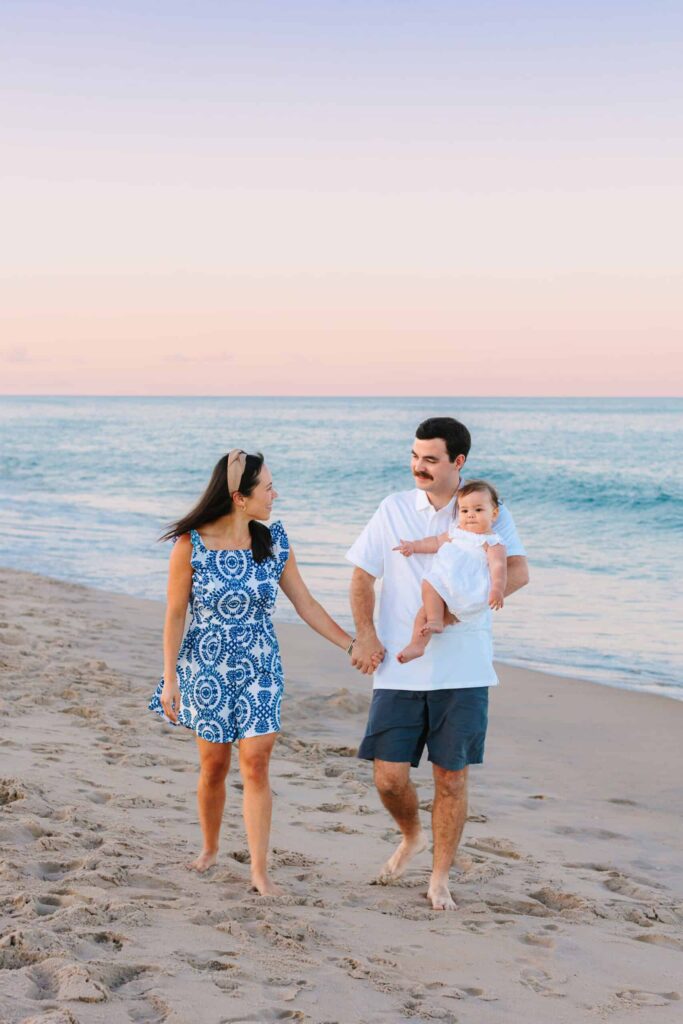 Smiling family walking on the beach during sunset, celebrating family moments with professional photos.