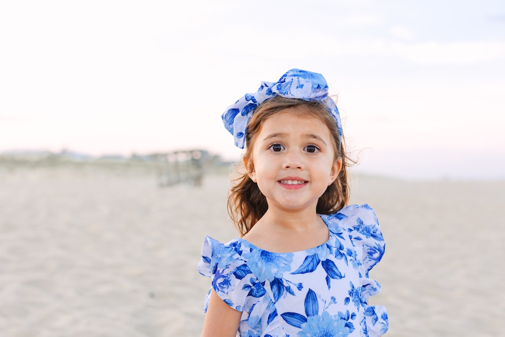 Young girl in blue floral dress during sunset family photos at Delaware beach
