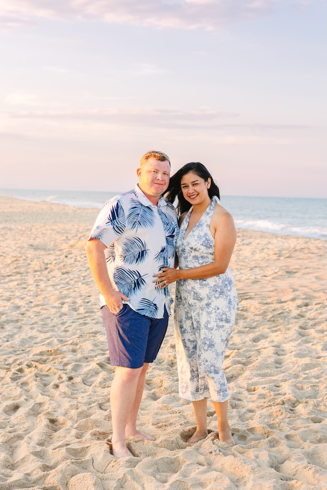 Couple smiling on the beach in Fenwick Island with a sunset